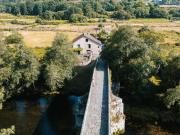 Casa de piedra reformada con jardín frente al puente...